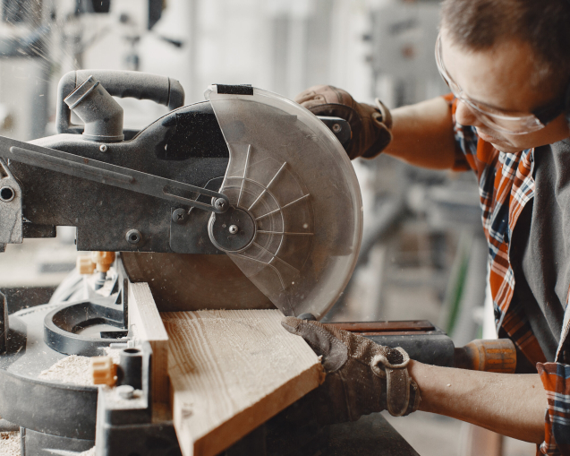 Wood cutting with circular saw. Closeup of mature man sawing lumber.